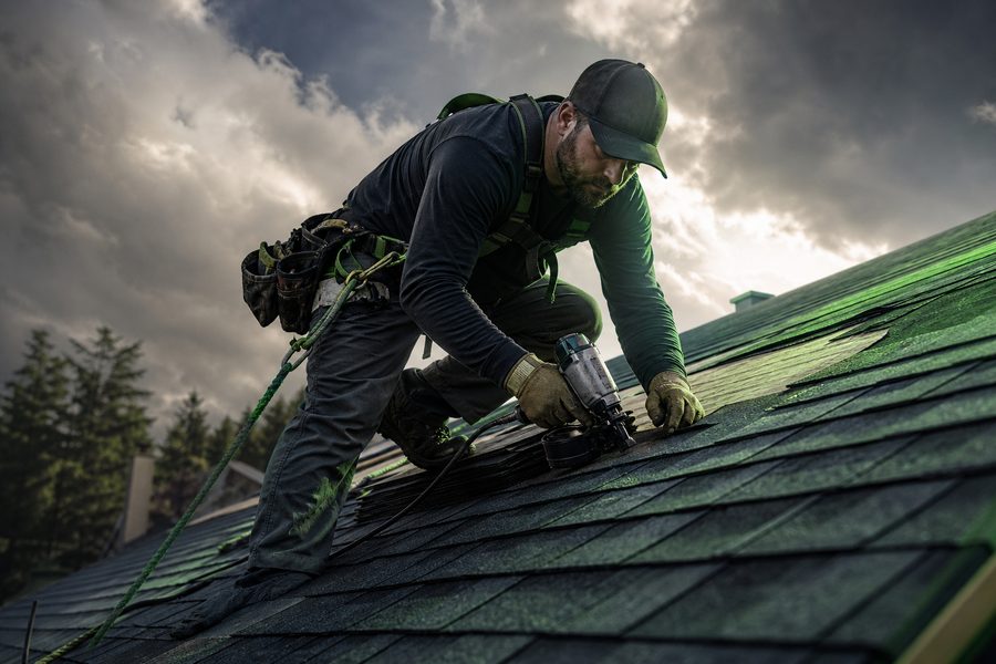 Roofer installing shingles on a residential roof